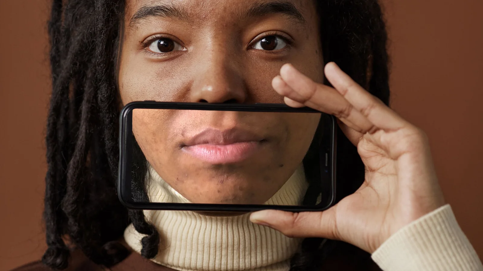 A woman looks through a clear phone case held in front of her face.