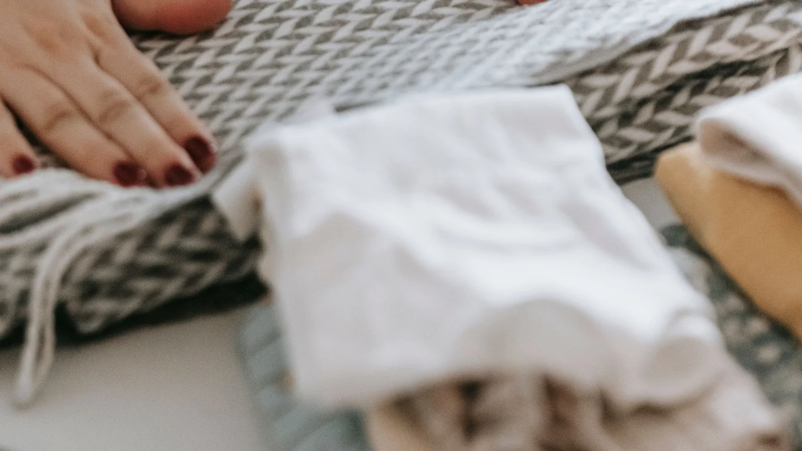 Hands rest on a small pile of freshly folded clothes.
