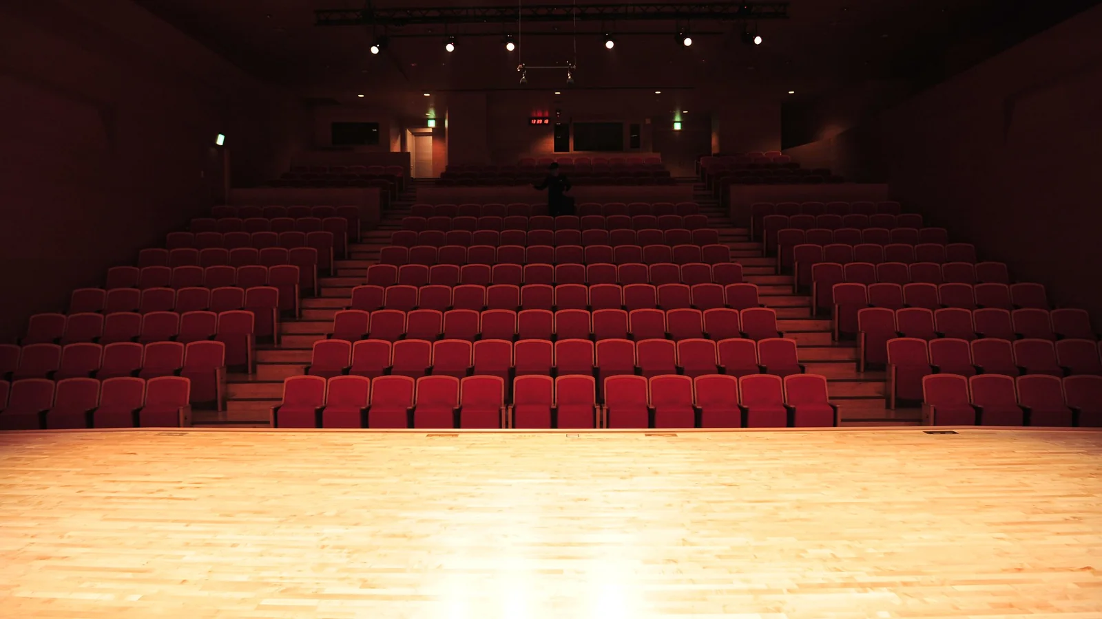 An empty theatre stage glows beneath warm lights.